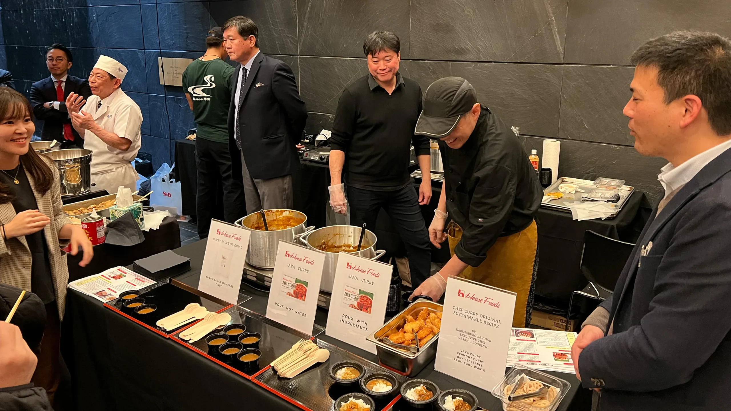 Chef serving Japanese curry samples to guests at a tasting event.